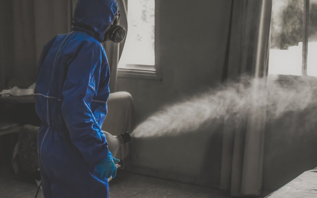 A person using a fogging machine to disinfect a room